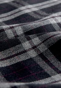 Tissu à carreaux noir et gris avec une texture fine ; présente des motifs à carreaux gris clair et violet foncé proéminents créant un effet de superposition.