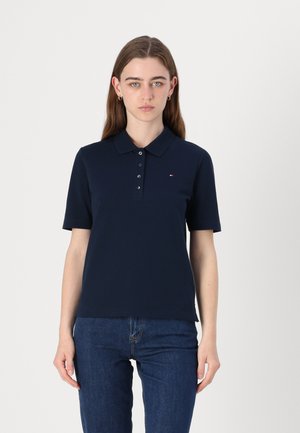 Námořnická modrá polo košile s límečkem, krátkými rukávy a zapínáním na knoflíky; obsahuje malé vyšívané logo na levém prsu.