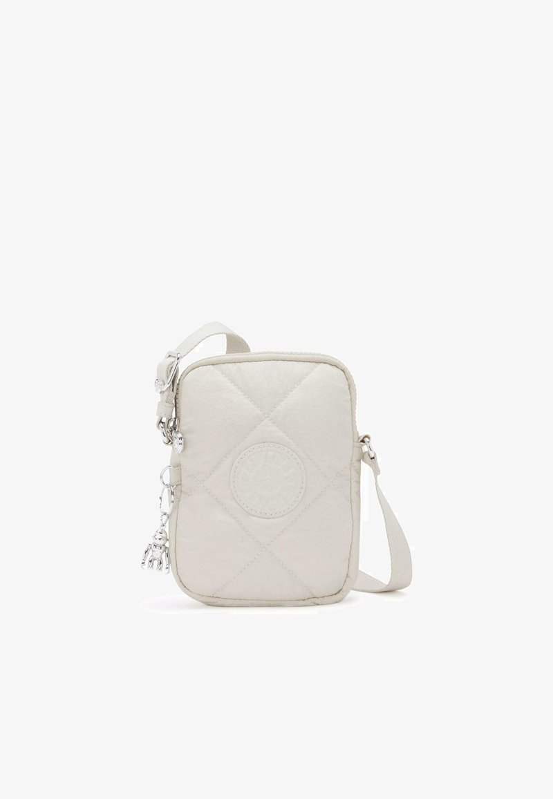 Kurtkowa, jasnobeżowa torebka crossbody z okrągłym logo i srebrnymi elementami ozdobnymi. Posiada odpinany pasek oraz zamek błyskawiczny.