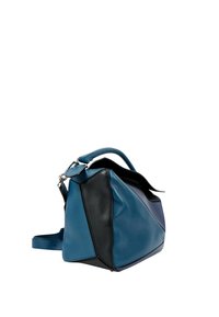 Sac à main en cuir bleu et noir avec panneaux géométriques, poignée supérieure et bandoulière amovible, placé sur fond blanc.