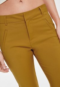 Mosterdgele op maat gemaakte broek met een stevige textuur, voorzien van zijzakken, riemlussen en een getailleerd ontwerp.