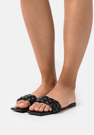 Chinelos pretos trançados com um design de bico quadrado e plano. Feitos de material texturizado, apresentam um acabamento trançado na parte superior e uma sola lisa.
