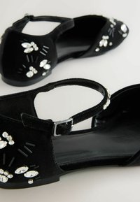 Czarne zamszowe baleriny z paskiem i klamrą, ozdobione przezroczystymi i czarnymi akcentami z kamieni szlachetnych, z gładką, płaską podeszwą.