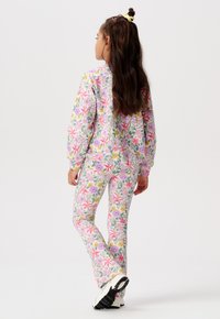 Ensemble de vêtements de détente à motif floral comprenant un haut à manches longues et un pantalon ajusté dans des couleurs pastel avec des fleurs roses, violettes et jaunes ; tissu doux.
