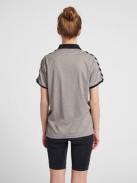 Grijze polo met een zwarte kraag en gestreepte accenten op de schouders, gecombineerd met donkere fietsbroekjes. Gladde textuur, casual pasvorm.