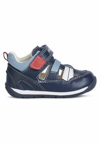 Zapato de piel azul marino para niños pequeños con correas de Velcro, detalles en blanco y punta texturizada. Presenta una suela flexible y un diseño ligero.