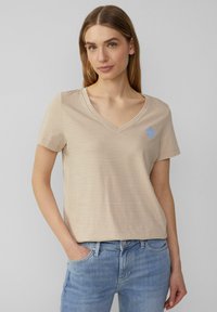 Beige gestreepte kortemouwen V-hals t-shirt met een blauw cirkelvormig logo-detail, gemaakt van zachte stof met een relaxte pasvorm.