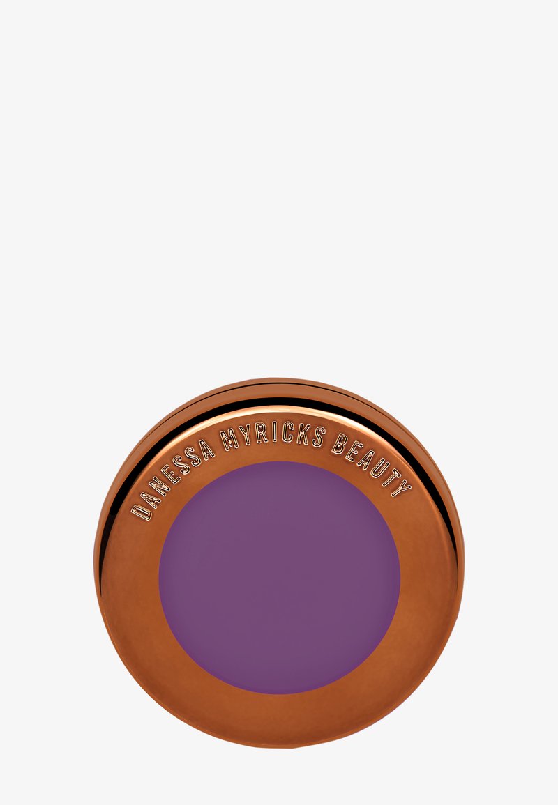 Compact rond contenant un produit violet lisse et mat. L'extérieur est en cuivre brillant avec un texte en relief indiquant "DANESSA MYRICKS BEAUTY."