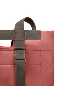 Roze gewatteerde stoffen draagtas met een bruine webbingriem en gesp, met een handvat aan de bovenkant en een gestructureerd oppervlak.