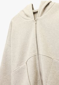 Hellgrauer Kapuzenpullover mit Reißverschluss vorne, aus weichem, strukturiertem Stoff, ausgestattet mit zwei Vordertaschen und einem minimalistischen Design.