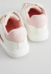 Weiße Sneaker mit pinken Akzenten, ausgestattet mit einem strukturierten Rückenteil, das mit "BAKER" geprägt ist, elastischen Riemen und einer glatten Lederoberfläche.