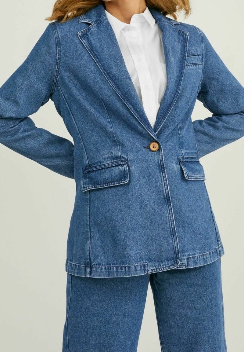 Džínové sako ve středně modré barvě, s jedním dřevěným knoflíkem, klopami s výřezem a dvěma předními kapsami s ozdobným prošitím.