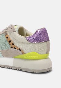 Baskets beiges avec détails vert clair et imprimé animal, talon violet pailleté, accent de midsole jaune néon et semelle extérieure en caoutchouc blanc.