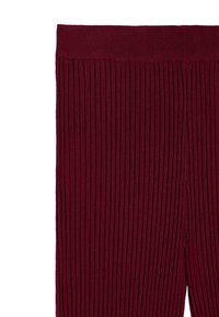 Bordowe prążkowane legginsy z szerokim, elastycznym pasem i pionową teksturą, wykonane z rozciągliwego, miękkiego materiału.
