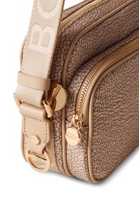 Sac bandoulière marron imprimé avec des zips dorés, une large sangle en tissu avec un logo et une finition texturée.