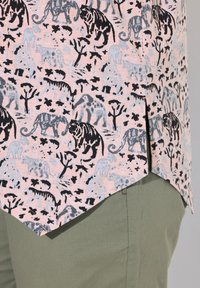 Camisa de estampado animal que presenta una tela rosa con diseños en gris y negro de tigres, elefantes y árboles, acabada con un dobladillo curvado.