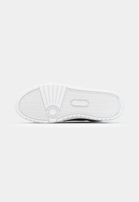 Talpa de sneaker alb din cauciuc cu un model în zigzag și un accent circular; zona brenduită afișează "LACOSTE" embossată.