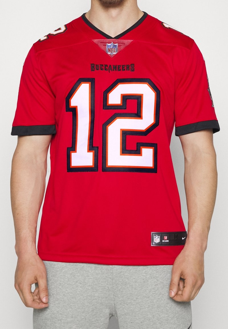 Punainen NFL-pelipaita, jossa joukkueen nimi "Buccaneers", pelaajan numero "12" valkoisena oransseilla yksityiskohdilla, hihoissa musta reuna ja edessä Nike-logo.