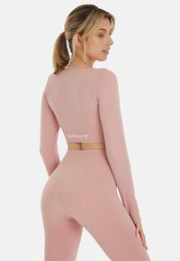 Conjunto de top deportivo corto y leggings en color rosa con un diseño ajustado, textura acanalada y logo "SQUATPROOF" en la cinturilla. Incluye mangas largas.