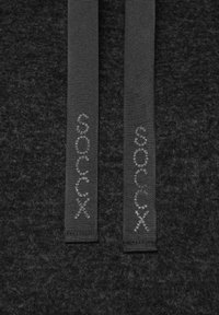Tessuto nero con una morbida texture presenta due cordini piatti grigi rifiniti con branding. Il design complessivo è semplice e minimalista.