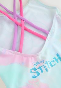 Kostium kąpielowy w wielokolorowy pastelowy gradient, z różowymi i fioletowymi paskami oraz błyszczącym niebieskim napisem "Stitch".