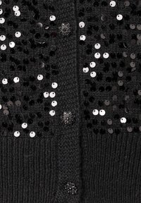 Schwarze Strickjacke mit glänzenden schwarzen und silbernen Pailletten, die aus strukturiertem Stoff besteht, auffällige Knopfdetails aufweist und eine weiche Oberfläche hat.
