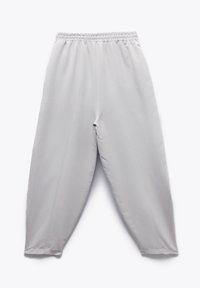 Lichtgrijze broek met een elastische tailleband, taps toelopende pijpen en twee verticale naden aan de voorkant, gemaakt van een gladde, lichte stof.