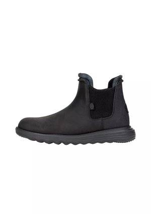 Stivaletto Chelsea nero alla caviglia con pannelli laterali elastici e suola texturizzata, progettato per un uso casual o all'aperto.