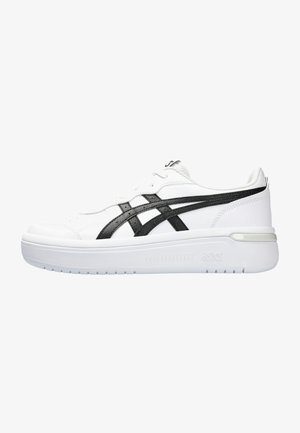 Chaussure de sport blanche avec des superpositions en synthétique noir, bout rond, semelle épaisse blanche et fermeture lacée. Design minimaliste avec des accents texturés.