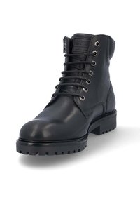 Bottines en cuir noir avec une pointe ronde, un laçage sur le devant, une fermeture éclair sur le côté et une finition texturée. Présente des œillets en métal et une semelle en caoutchouc épaisse.