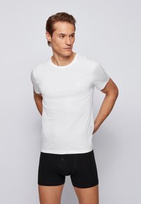 Witte T-shirt met korte mouwen gemaakt van glad stof, met een ronde halslijn en een subtiele logo op de borst, gecombineerd met zwarte shorts.