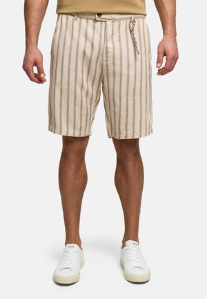 Shorts beige pour hommes avec des rayures verticales marron, associés à des baskets blanches Veja, montrés de la taille aux pieds sur un fond uni.