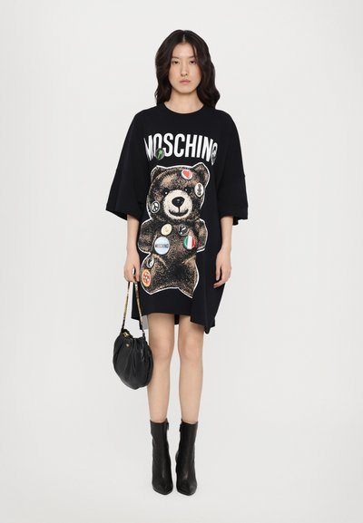 Μαύρο υπερμεγέθες φόρεμα μπλούζα με γραφικό αρκούδας και διάφορες πολύχρωμες επιφάνειες, με σήμανση "Moschino" και κοντά μανίκια.