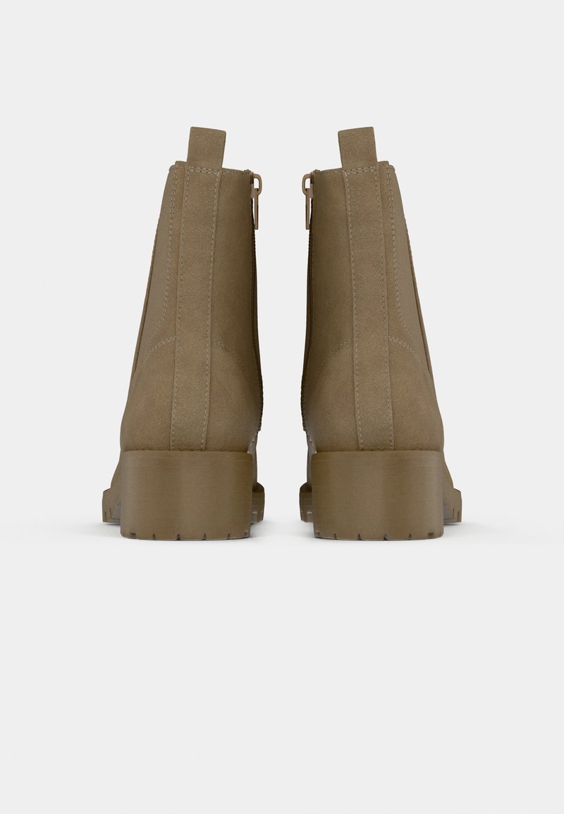 Paire de bottines en daim marron avec talons épais et languettes, vues de dos sur fond blanc.
