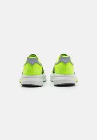 Neon yellow athletic shoes with a textured upper, gray accents on the heels, and a cushioned white sole. Rear view displayed.