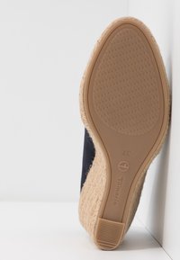 Marine stofoverdel med en jute-indsvøbt sål. Sålen har et tekstureret gummimønster for bedre greb, og et lille logo er synligt på siden.