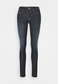 Vaqueros ajustados de color azul oscuro, hechos de mezclilla, con cinco bolsillos, cierre frontal con botón y un ligero desgaste en las piernas.