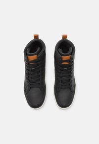 Black high-top sneakers featuring a smooth leather exterior, black laces, and a tan accent on the tongue, with a white rubber sole.