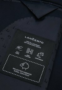 Granatowy materiał o miękkiej fakturze z czarną metką, na której znajdują się instrukcje pielęgnacji, w tym właściwości miękkiego dotyku, antygniotliwości oraz lekkiej wagi.