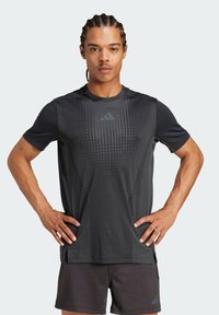 T-shirt de sport noir à manches courtes, avec des rayures verticales et un logo discret sur la poitrine. Fabriqué en matériau léger et respirant.