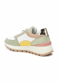 Las zapatillas presentan materiales de ante y sintéticos en verde, blanco, amarillo y rosa. Suela gruesa con tacos marrones y acentos metálicos en el talón.
