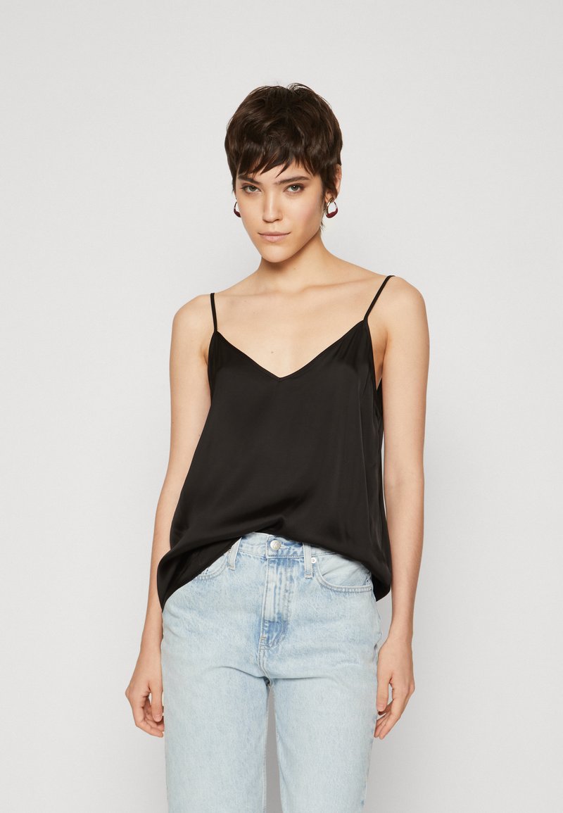 Black satin camisole with thin straps, V-neck design, soft texture, and loose fit, paired with light blue high-waisted jeans.