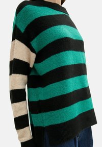 Grüner und schwarzer gestreifter Pullover mit beigem Ärmel. Weicher Stoff, gerippter Saum und seitliche Schlitze. Lässiger, entspannter Schnitt.