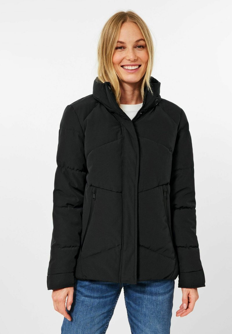 Giacca a vento nera con colletto alto, chiusura frontale con zip, due tasche laterali con zip e pannellatura testurizzata sulle spalle.