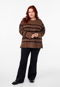 Maglione a righe marroni con strisce nere, maniche lunghe e vestibilità comoda. Abbinato a pantaloni svasati neri e scarpe nere.