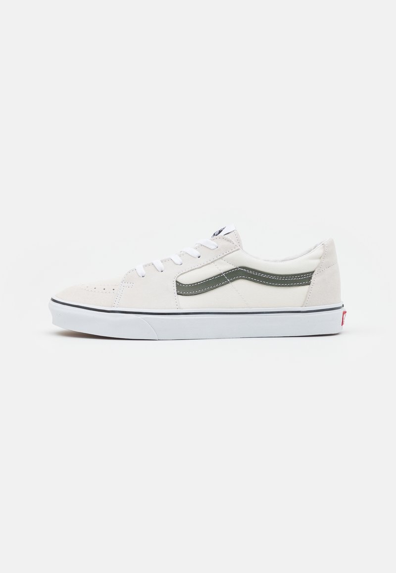 Białe zamszowe sneakersy z oliwkowymi akcentami, okrągły czubek, białe sznurowadła oraz gumowa podeszwa z czarnym pasem i czerwonym logo na pięcie.