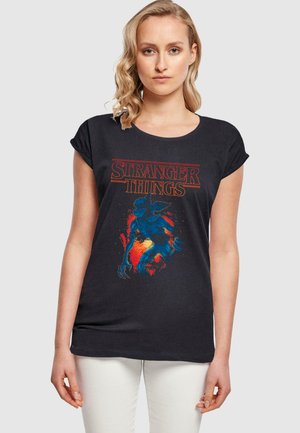 Schwarzes Kurzarm-T-Shirt mit einem "Stranger Things"-Grafikdesign in Rot und Blau, versehen mit einer Monsterillustration auf einem strukturierten Hintergrund.