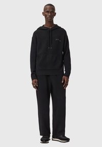 Schwarzes Hoodie- und Jogginghosen-Set aus weichem Stoff; verfügt über eine Kängurutasche und eine Kapuze mit Kordelzug; enthält dezente Stickereien.