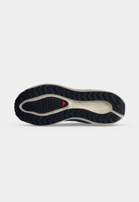 Σόλα παπουτσιού με μαύρο πέλμα, λευκή ενδιάμεση σόλα, εξαγωνικά και ζιγκ-ζαγκ μοτίβα και μια μικρή κόκκινη τριγωνική λεπτομέρεια κοντά στο κέντρο.