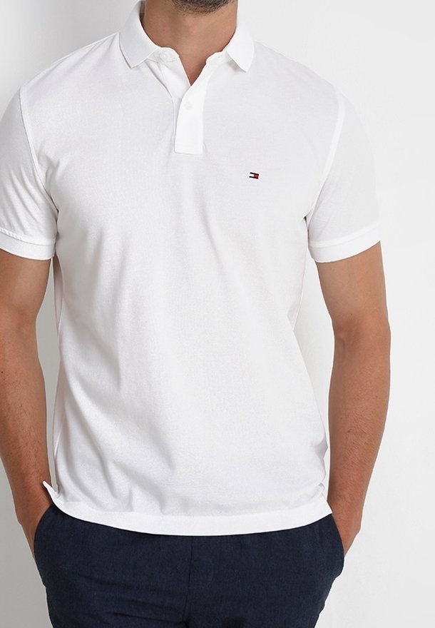 Polo blanc à manches courtes, avec un col et un logo discret sur la poitrine. Fabriqué en coton lisse.